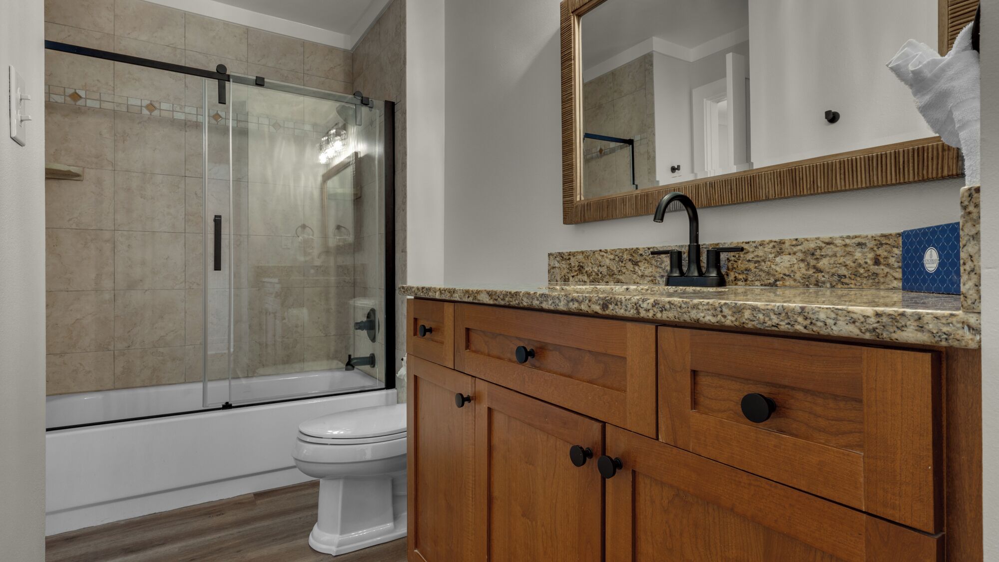A bathroom with a shower, toilet, vanity, and mirror.
