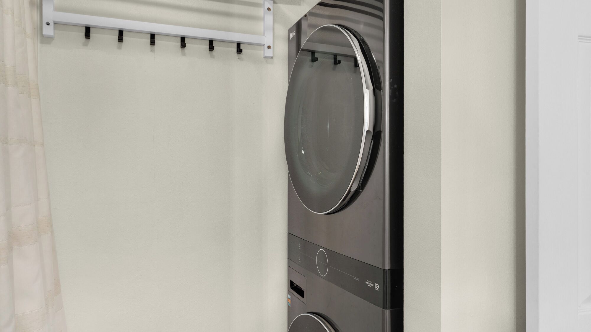 A wall-mounted washing machine with a control panel and a white towel rack above it.