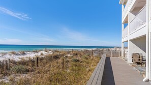 A beachside hotel with a wooden boardwalk leading to a balcony with outdoor seating. - Eastern Shores (Santa Rosa Beach)