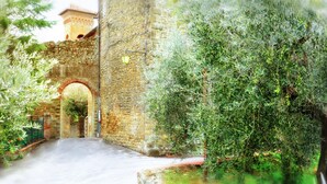 A narrow stone pathway leading to a stone archway, surrounded by lush greenery and a stone wall. - Fondaco del Moro (Civitella in Val di Chiana)