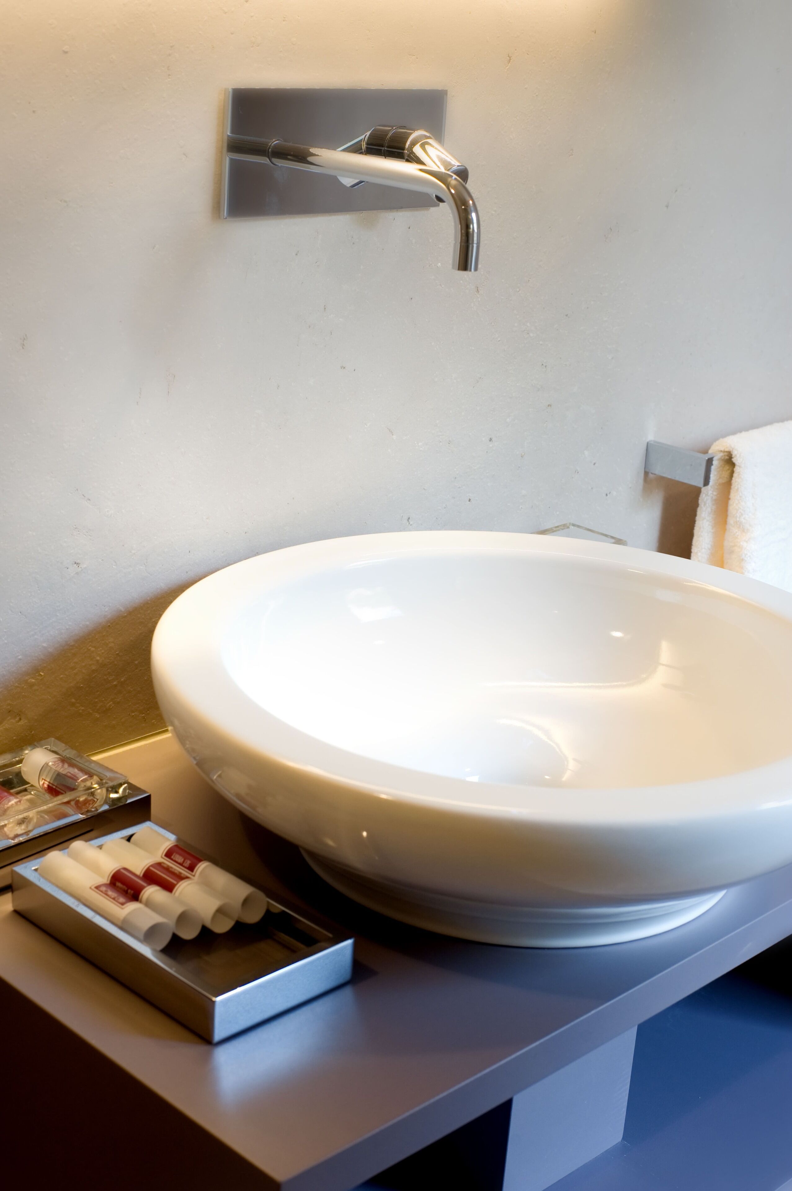 Ein Badezimmer mit einem weißen Waschbecken, einem Handtuchhalter und einer Seifenspender.