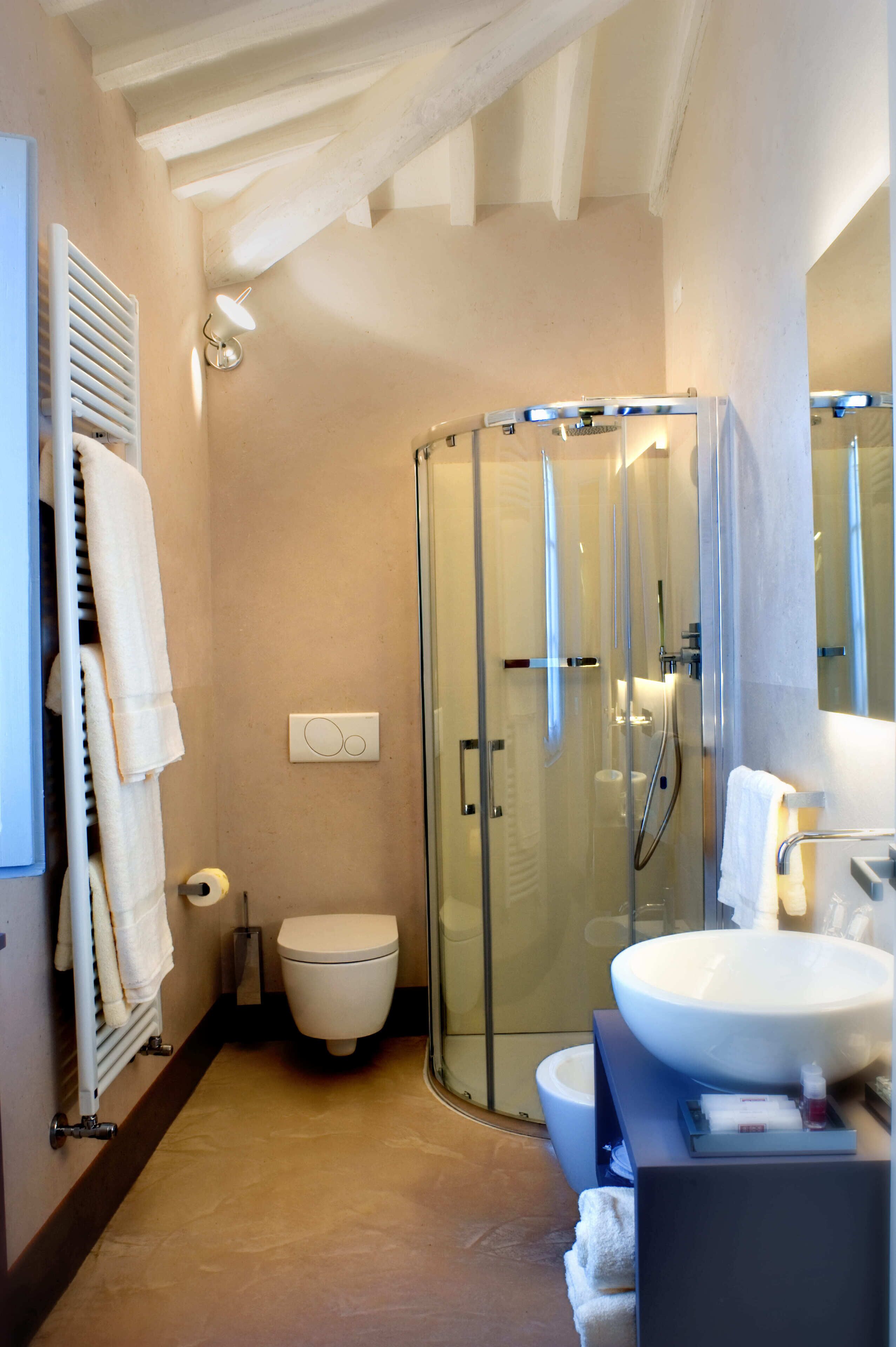 Een moderne badkamer met een douchekabinet van glas, een wit toilet en een groot wastafel.