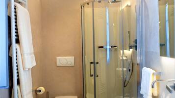 Een moderne badkamer met een douchekabinet van glas, een wit toilet en een groot wastafel.