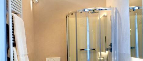 Un baño moderno con ducha de mampara de vidrio, inodoro blanco y lavamanos grande.