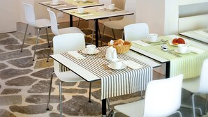 A dining area with a table set for two, white chairs, and a stone-patterned floor. - Fondaco del Moro (Civitella in Val di Chiana)