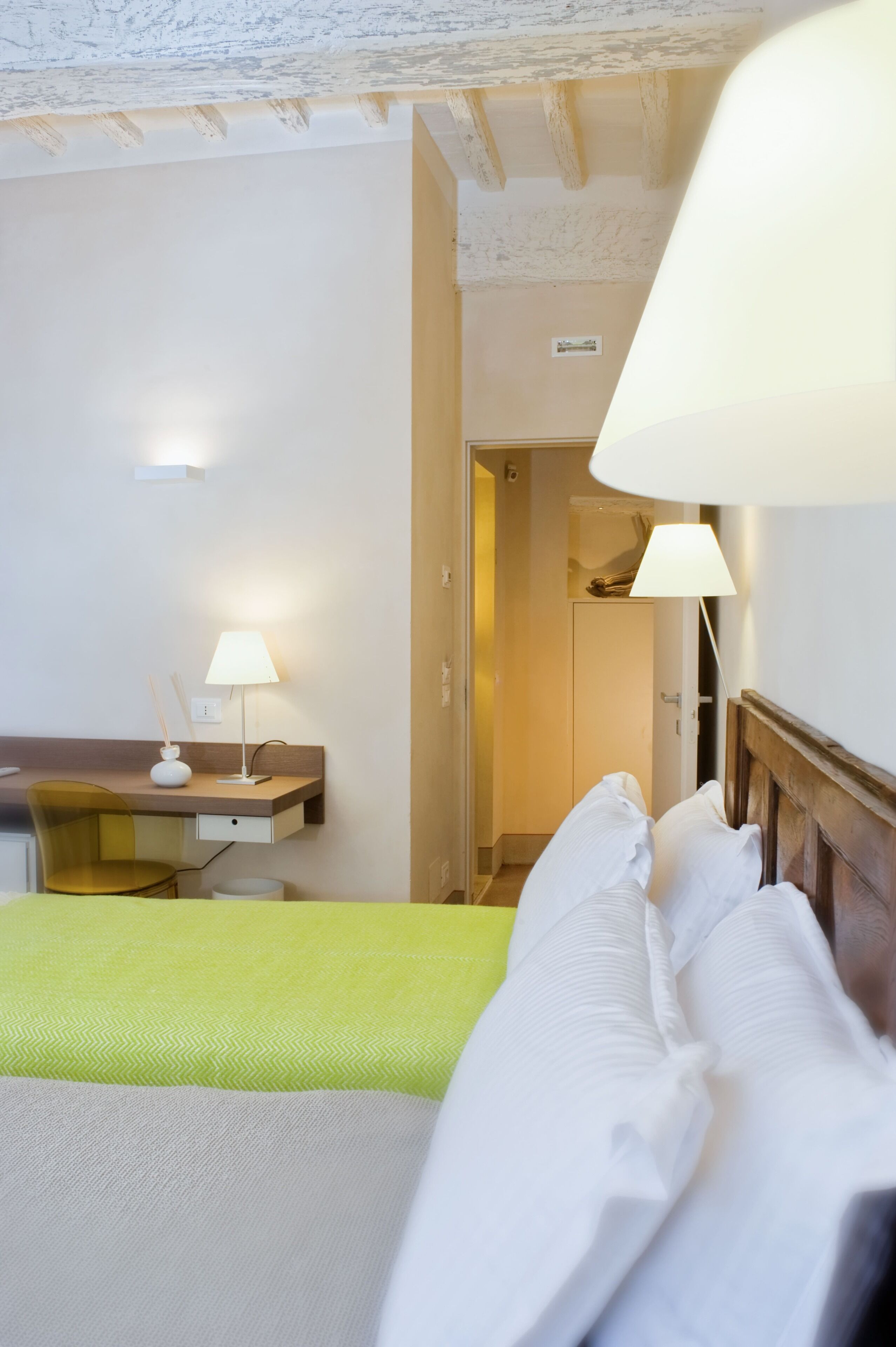 Una habitación de hotel con una cama, un escritorio con lámpara y una silla.