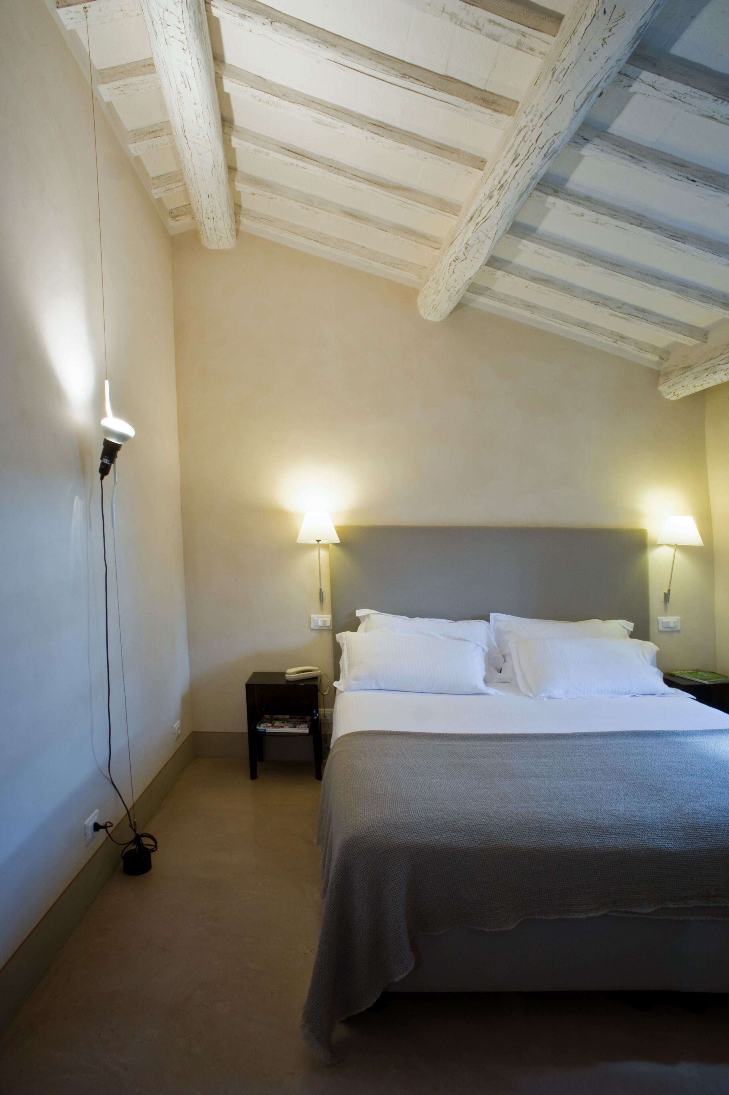 Una camera da letto con un letto, due abat-jour, un comodino e una presa a muro.