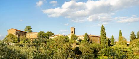 A historic building with a bell tower, surrounded by lush greenery and trees.