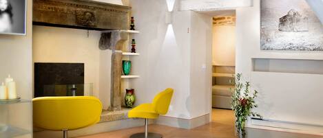 A modern interior with a yellow chair, a fireplace, and a staircase.