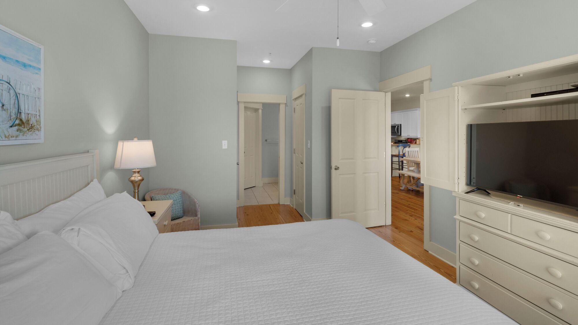 Une chambre à coucher comprenant un lit, une table de chevet, une lampe, une chaise, une commode et un téléviseur.