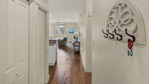 A hallway with wooden flooring, white walls, and a decorative wall piece. - Grand Isle (Santa Rosa Beach)