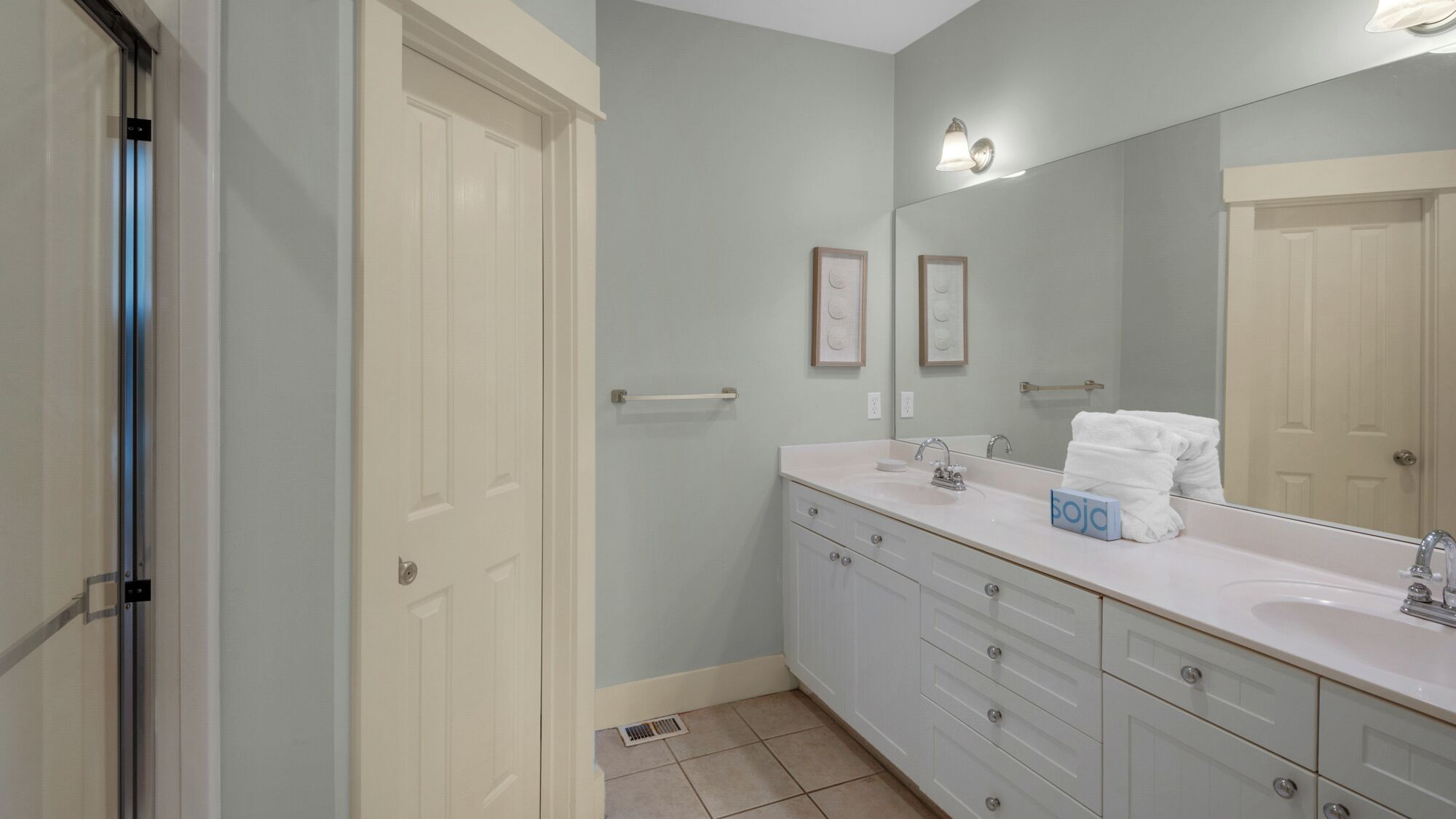 A bathroom with a white vanity, a large mirror, and a towel rack.
