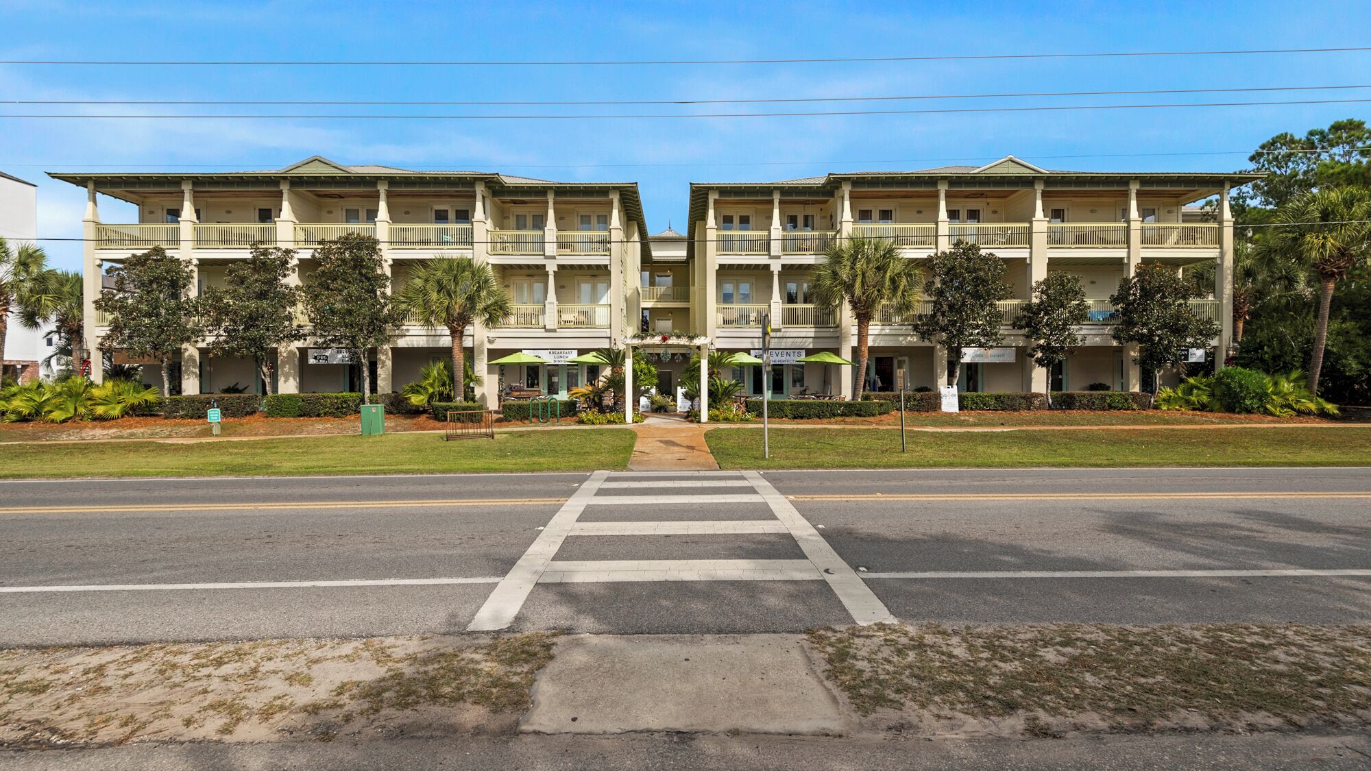 A two-story hotel with a central entrance, balconies on each floor, and a well-maintained lawn.