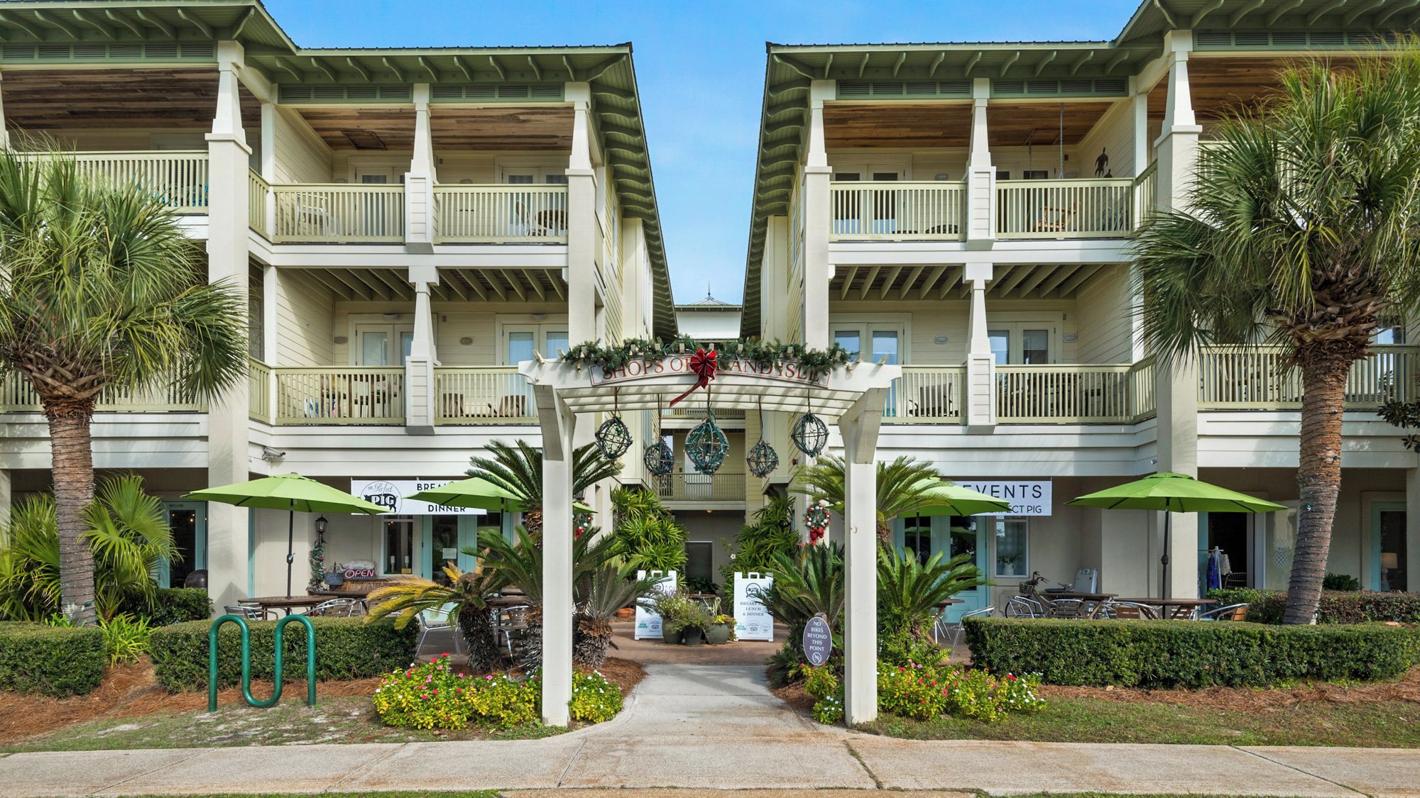 A hotel with a central entrance, multiple balconies, and outdoor seating areas.