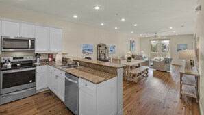 A modern kitchen with white cabinetry, stainless steel appliances, and a granite countertop. - Grand Isle (Santa Rosa Beach)