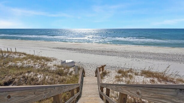 A wooden boardwalk leading to a beach with sand and sparse vegetation. - Grand Isle (Santa Rosa Beach)