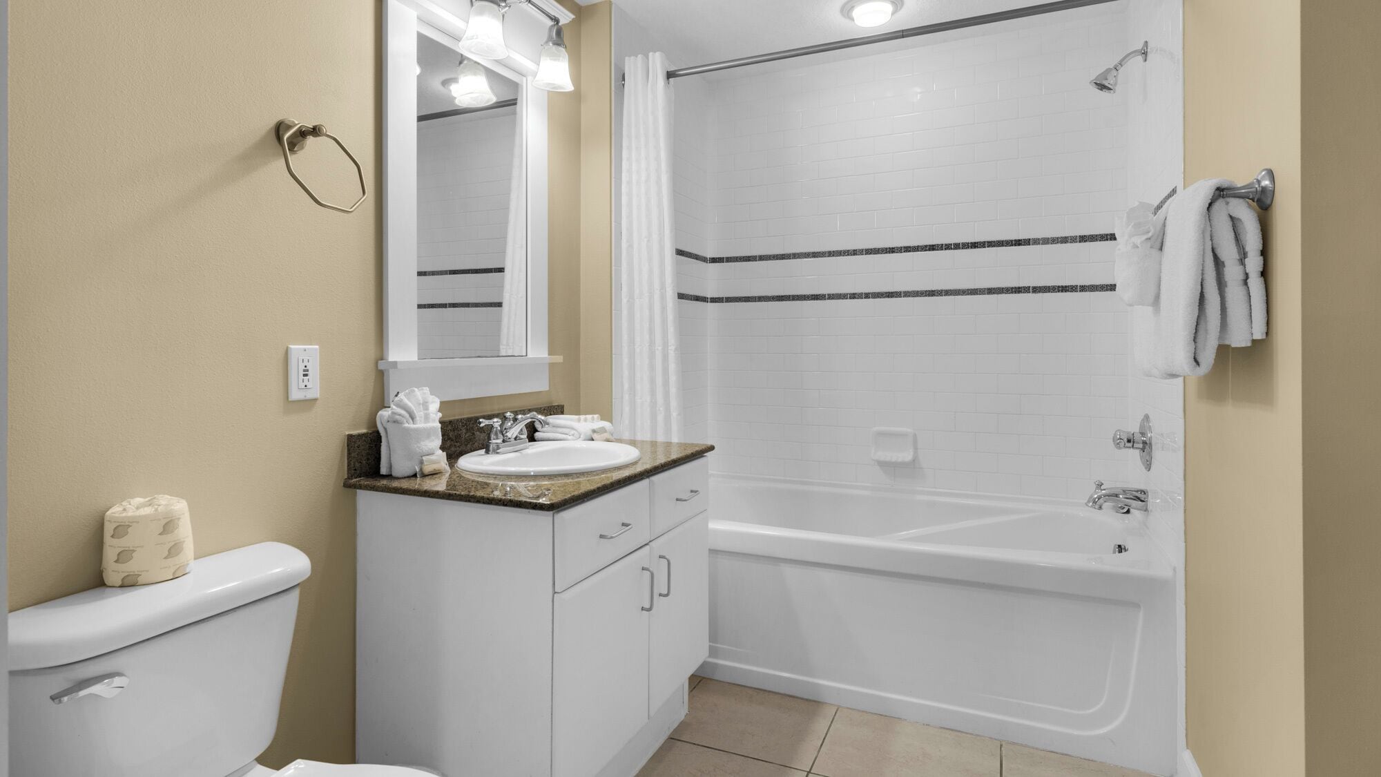 A bathroom with a toilet, sink, mirror, and shower.