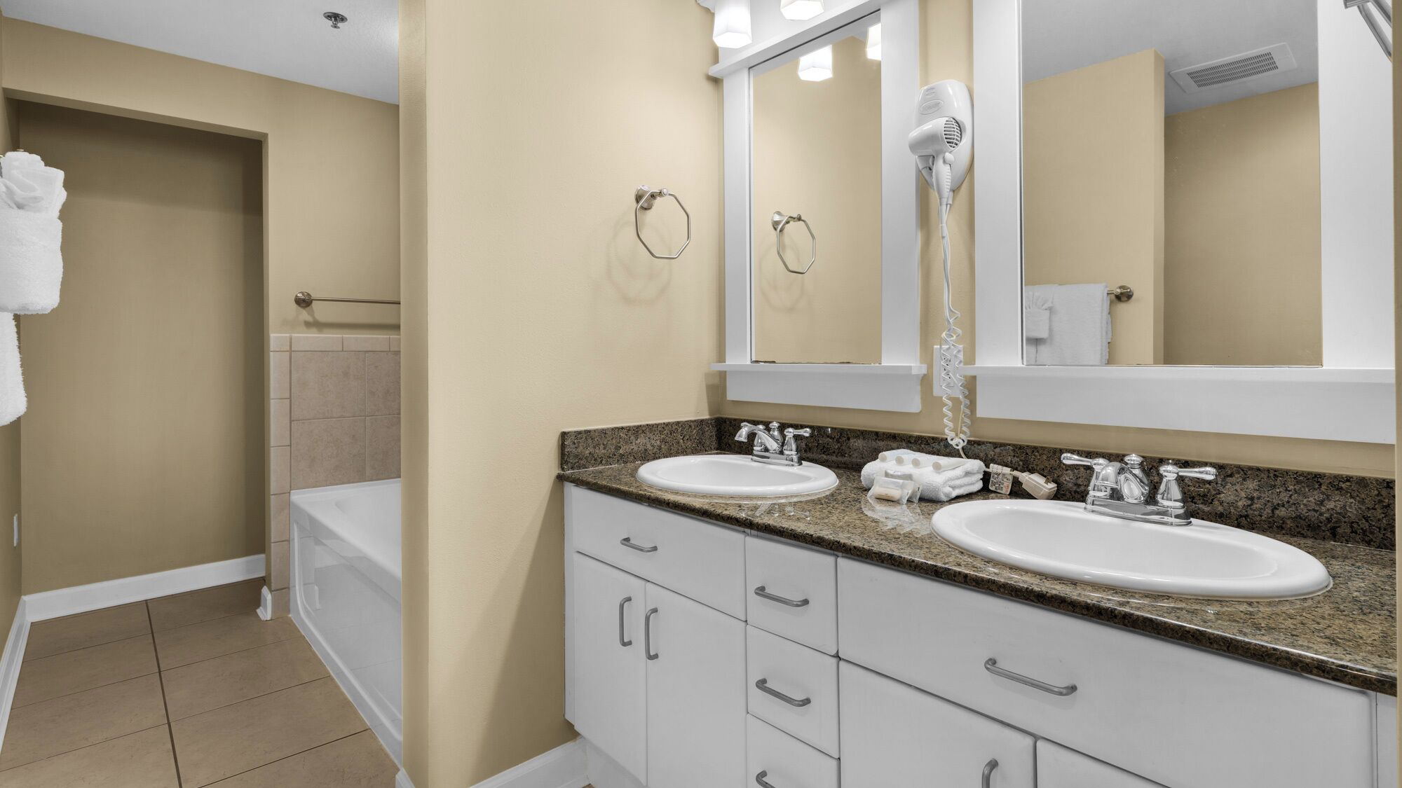 Une salle de bain moderne avec deux lavabos, un grand miroir et un sèche-cheveux.