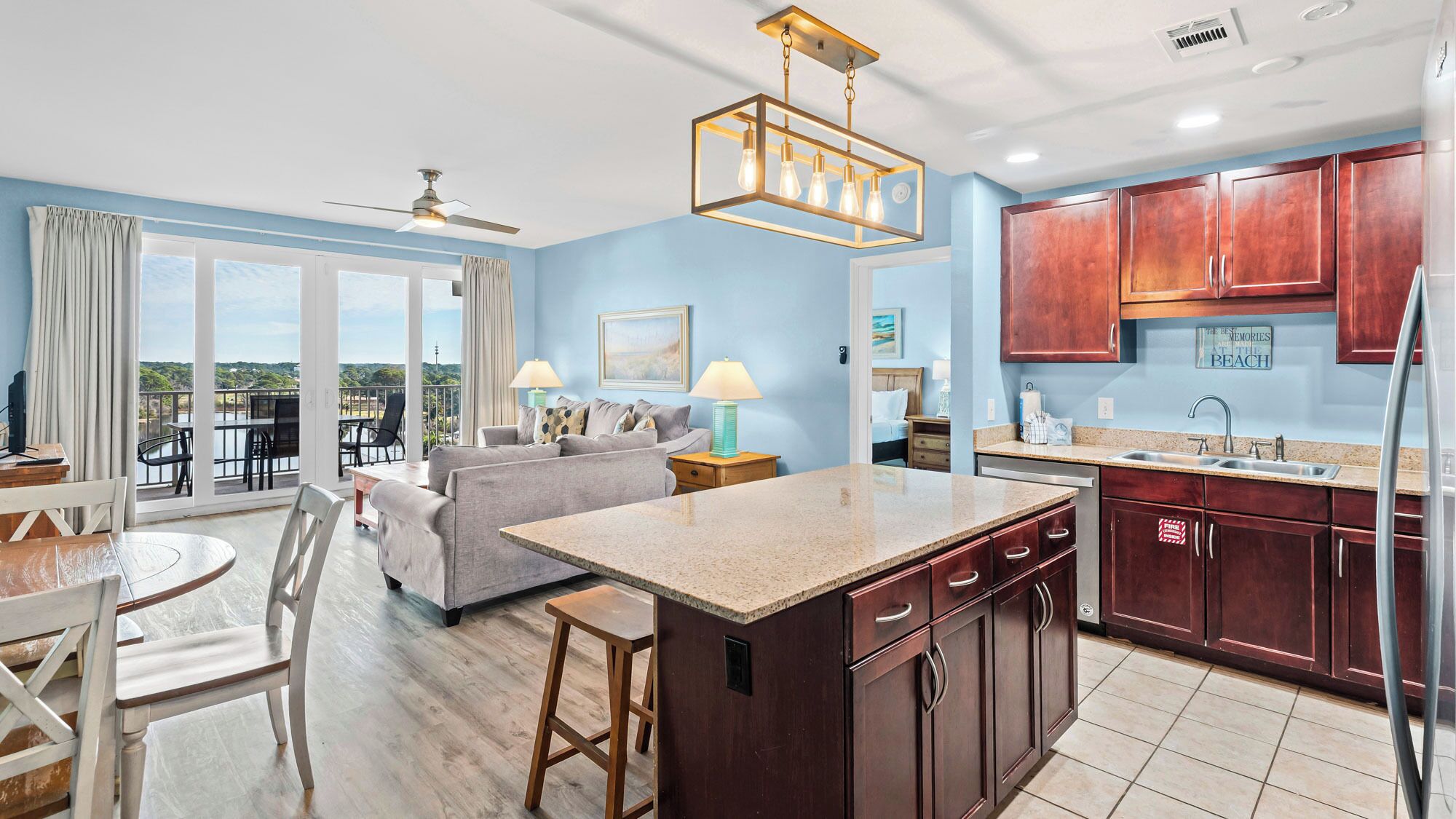 A modern kitchen with wooden cabinets, a central island, and a dining area with a round table and chairs.
