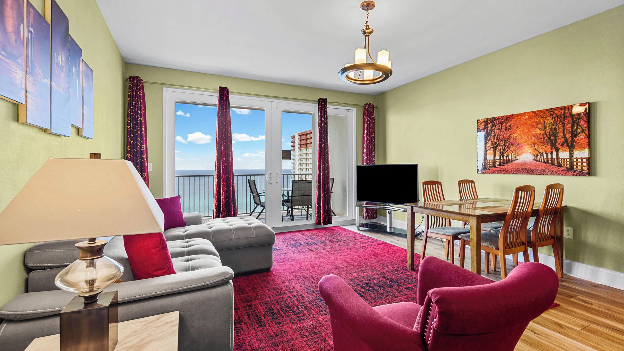 A living room with a sofa, a red armchair, a TV, and a dining area with chairs and a table.