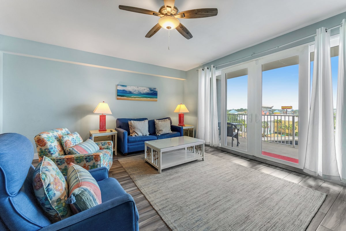 A living room with a blue sofa, a white coffee table, and a ceiling fan.