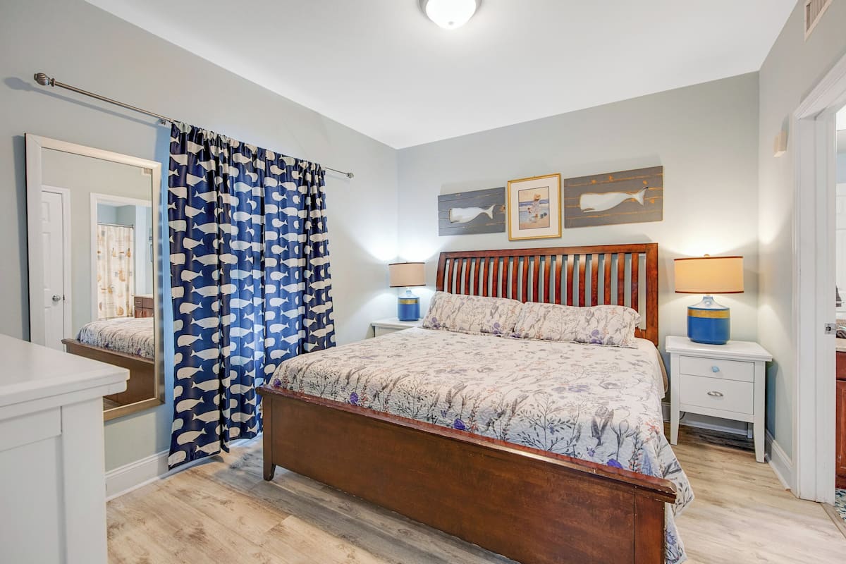 Cozy bedroom with a central bed, bedside tables, and a mirror above, offering a peaceful retreat.