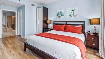 A hotel room with a large bed, two bedside tables, a wardrobe, and artwork on the wall.
