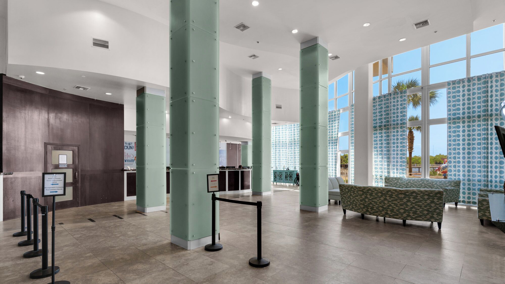 A spacious lobby with high ceilings, large windows, and a reception desk.