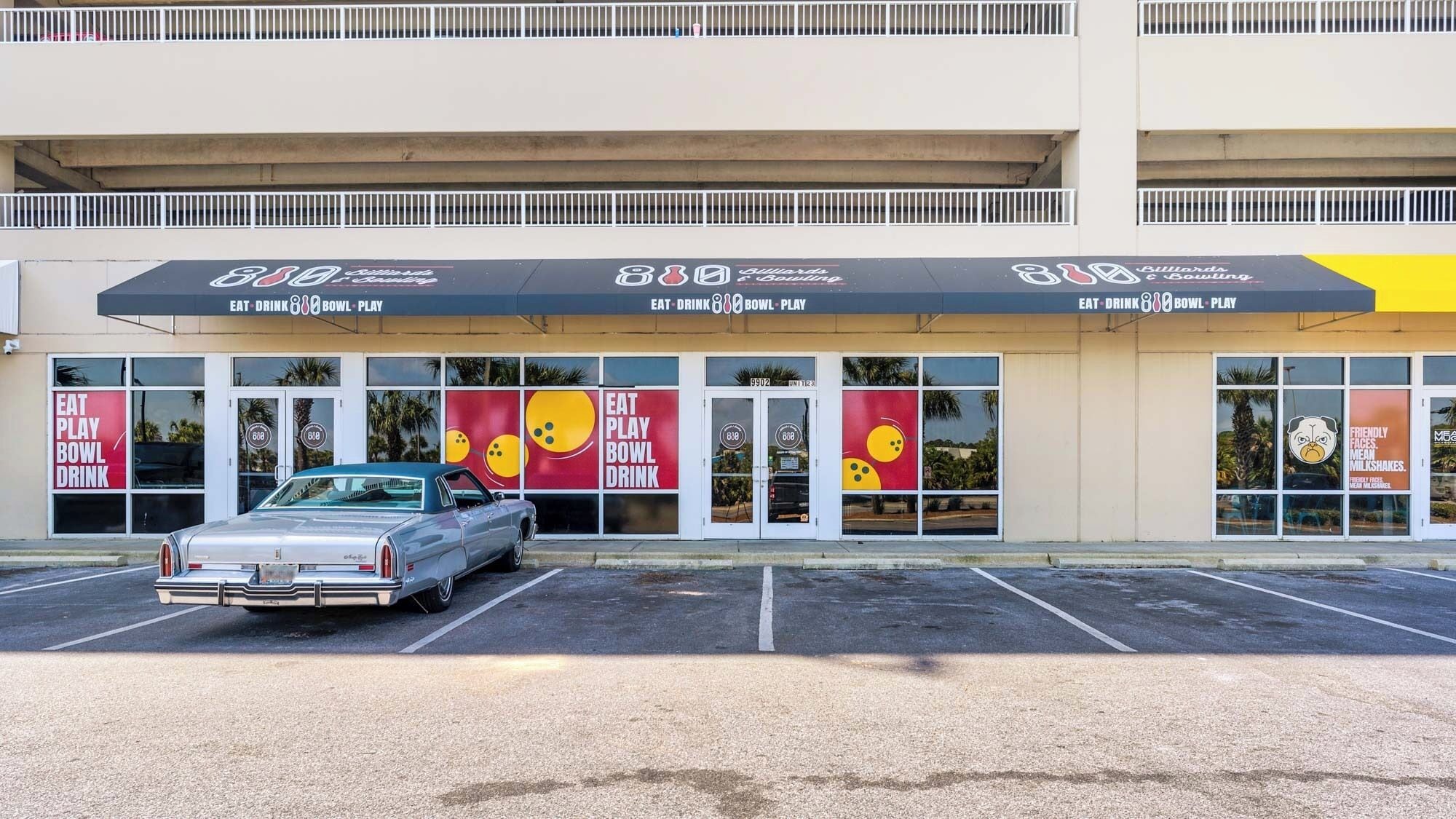 A bowling alley with a vintage car parked in front.