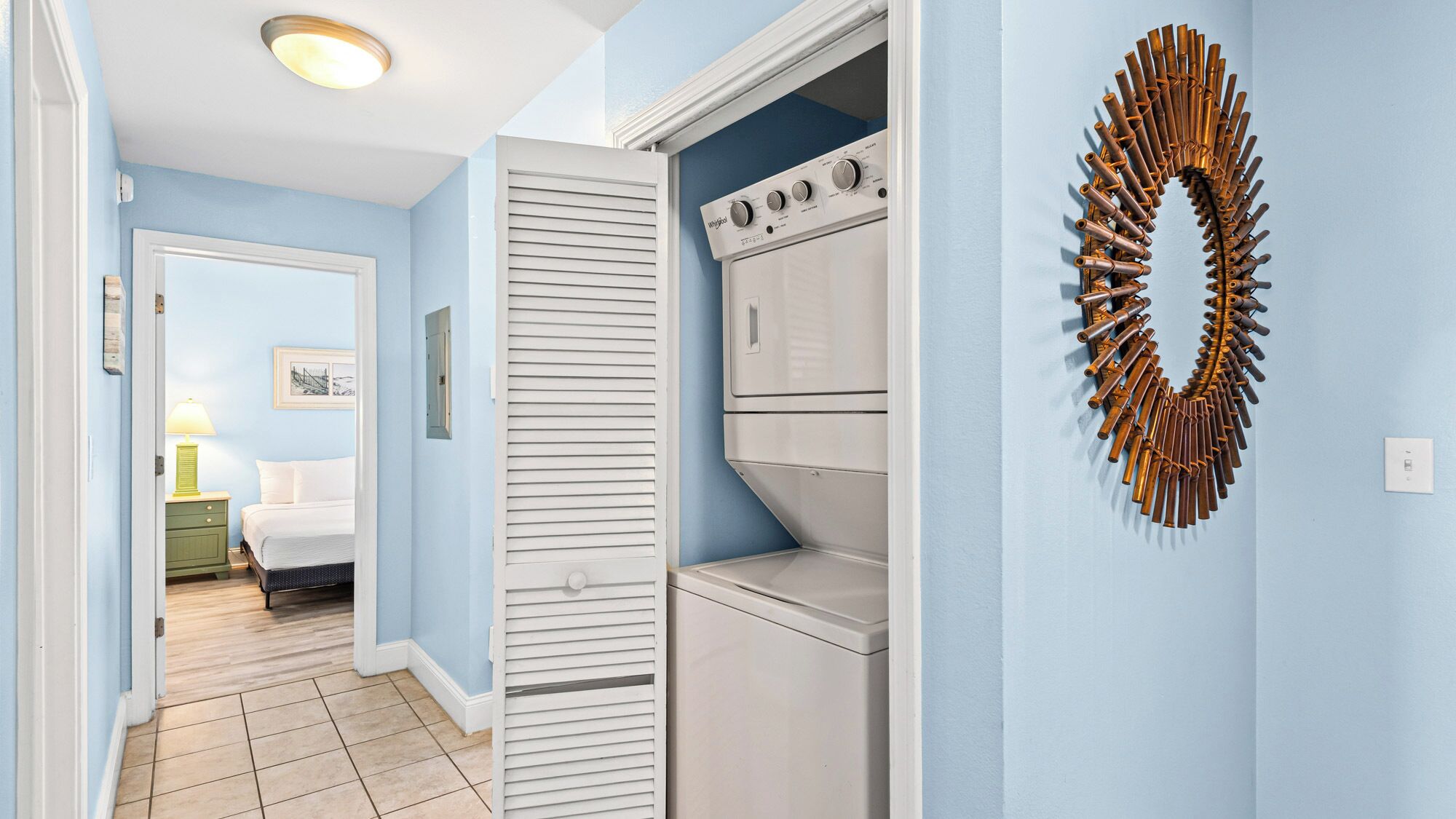 A laundry room with a white washer and dryer, a wooden door, and a decorative wall piece.