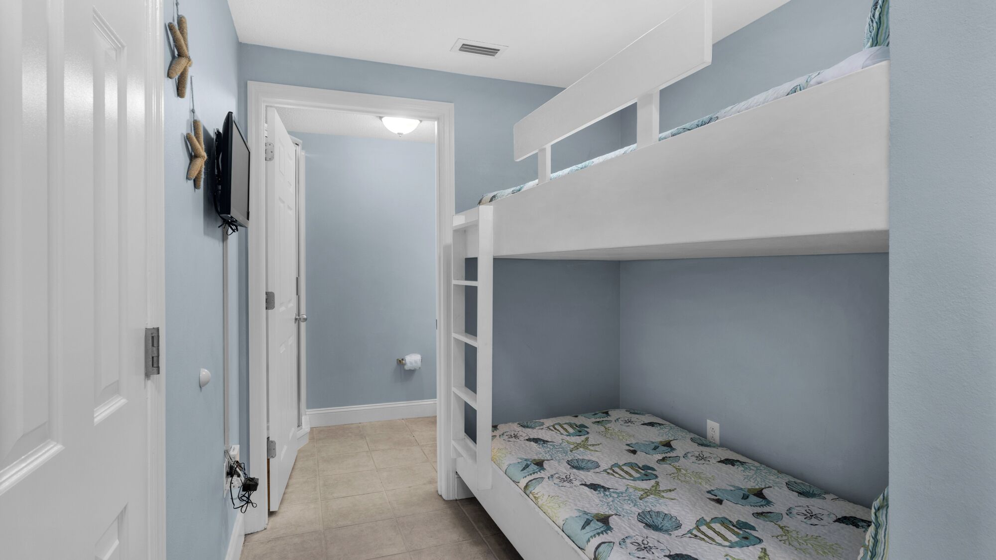 Une chambre avec des lits superposés, une porte et un interrupteur sur le mur.