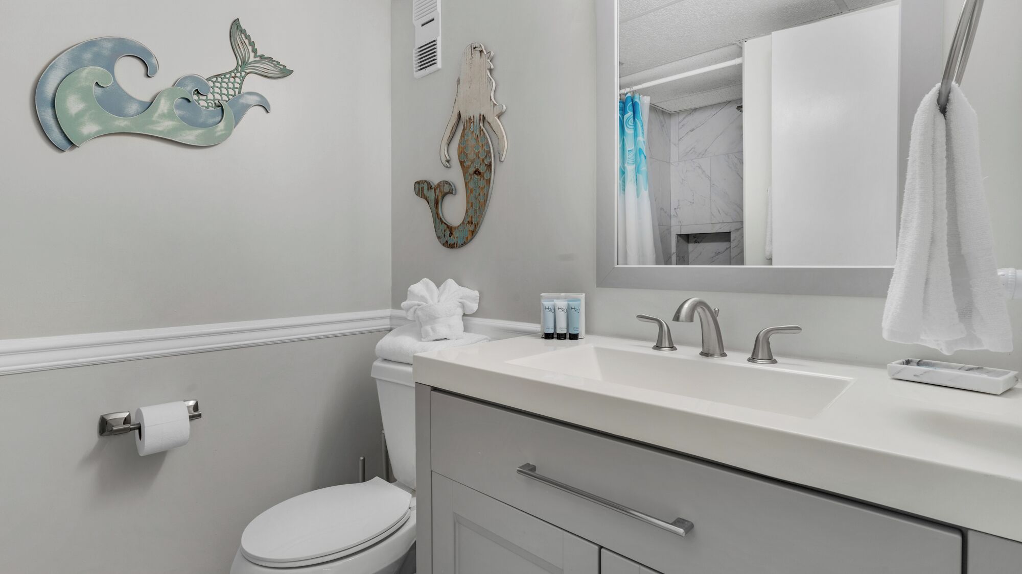 A modern bathroom with a toilet, sink, and mirror.