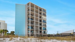 A multi-story hotel with a light blue facade, multiple balconies, and a beach view. - Moondrifter Condominiums (Panama City Beach)