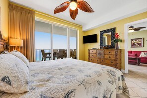 A bedroom with a large bed, a dresser, a TV, and a balcony with a view. - Ocean Reef (Panama City Beach)