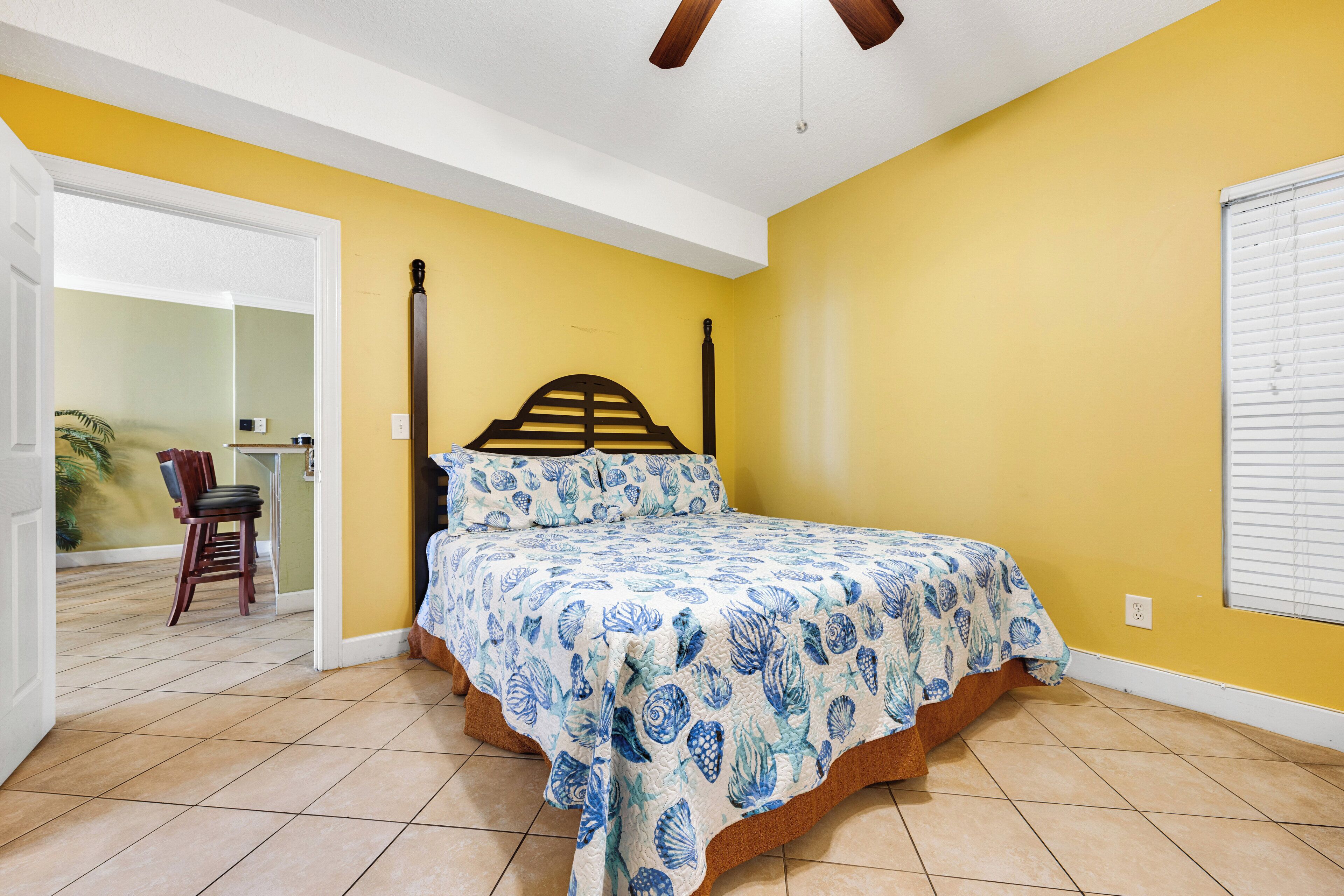 A bedroom with a bed, a ceiling fan, and a window with blinds.