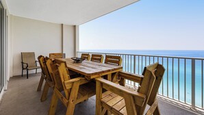 Ein Holztisch und Stühle auf einem Balkon mit Blick auf das Meer.