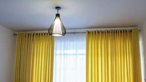 A room with yellow curtains, a hanging light fixture, and a window with sheer curtains. - Apartment Sleeps 4, 2 Baths, Free Parking (Harare)