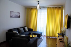 Una sala de estar con un sofá modular, una mesa de centro y un cuadro en la pared.