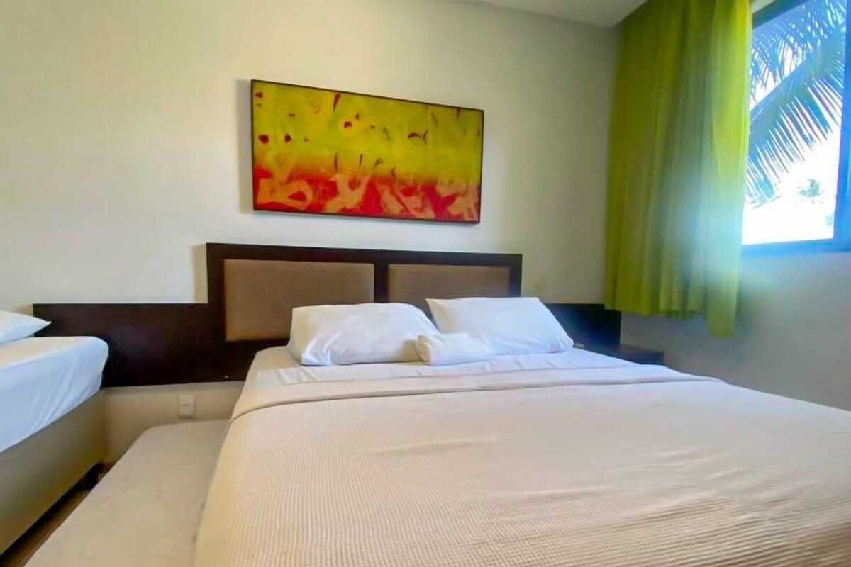 A hotel room with a large bed, a headboard, and a painting on the wall.