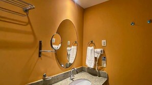 Une salle de bain équipée d’un lavabo, d’un miroir, d’un porte-serviettes et d’un sèche-serviettes.