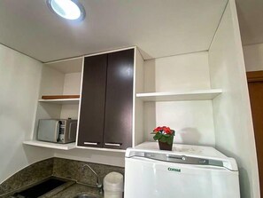 A compact kitchen with a built-in washing machine, a microwave, and a sink.