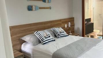 A neatly made bed with striped pillows, a wooden headboard, and an air conditioning unit above.