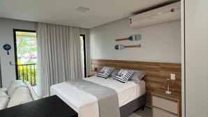Une chambre à coucher moderne, équipée d’un lit, de tables de chevet, d’un bureau et offrant une vue sur l’extérieur.