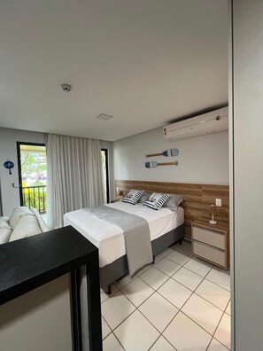 A modern bedroom with a bed, bedside tables, a desk, and a view of the outdoors. - Marulhos Suítes Porto de Galinhas (Ipojuca)