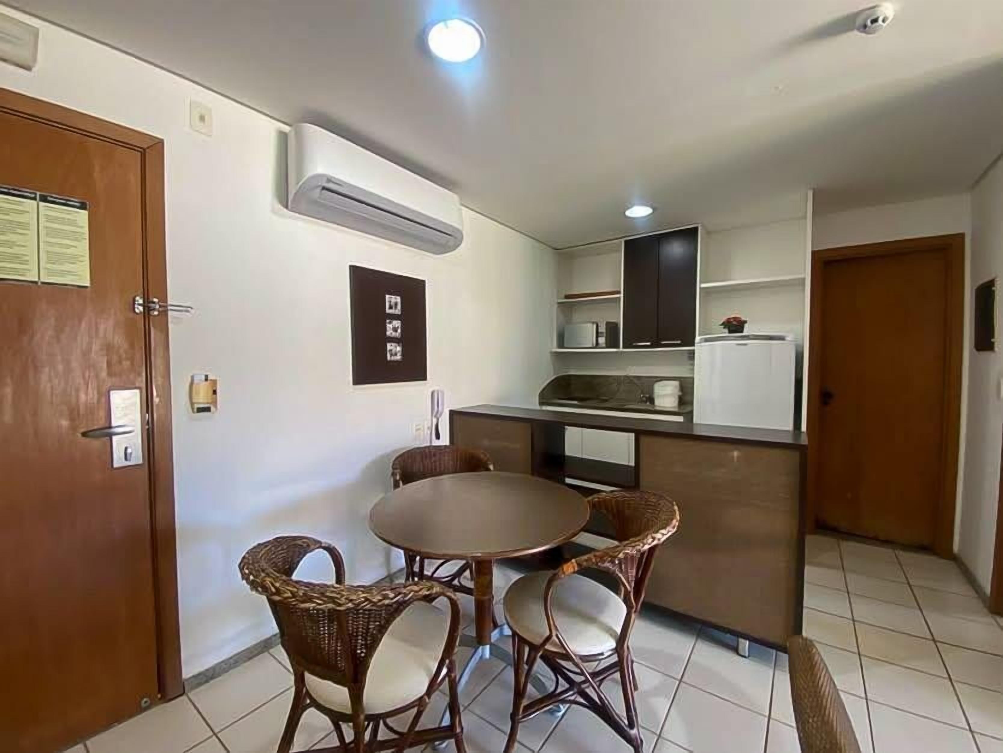 A compact kitchen with a dining area, including wicker chairs and a round table.