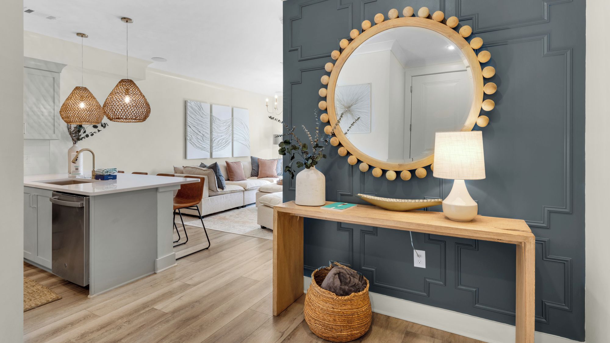 A modern kitchen with a central island, pendant lights, and a large mirror with a wooden frame.