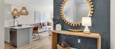 A modern kitchen with a central island, pendant lights, and a large mirror with a wooden frame.