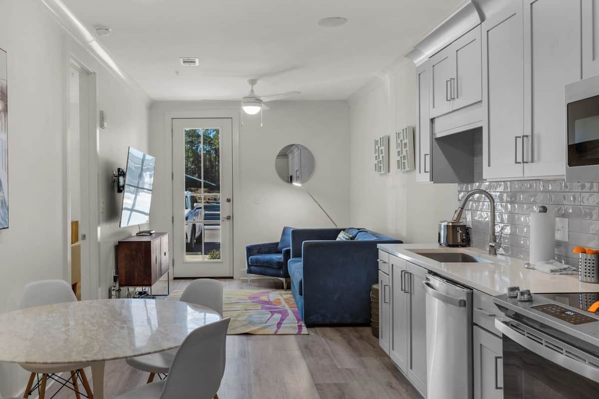 A modern kitchen with white cabinets, a built-in oven, and a stainless steel sink.