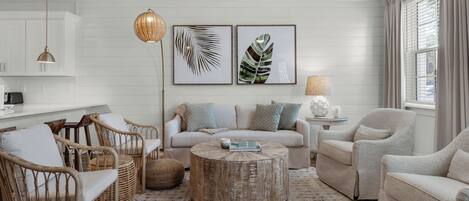 A living room with a sofa, chairs, a coffee table, and artwork on the wall.