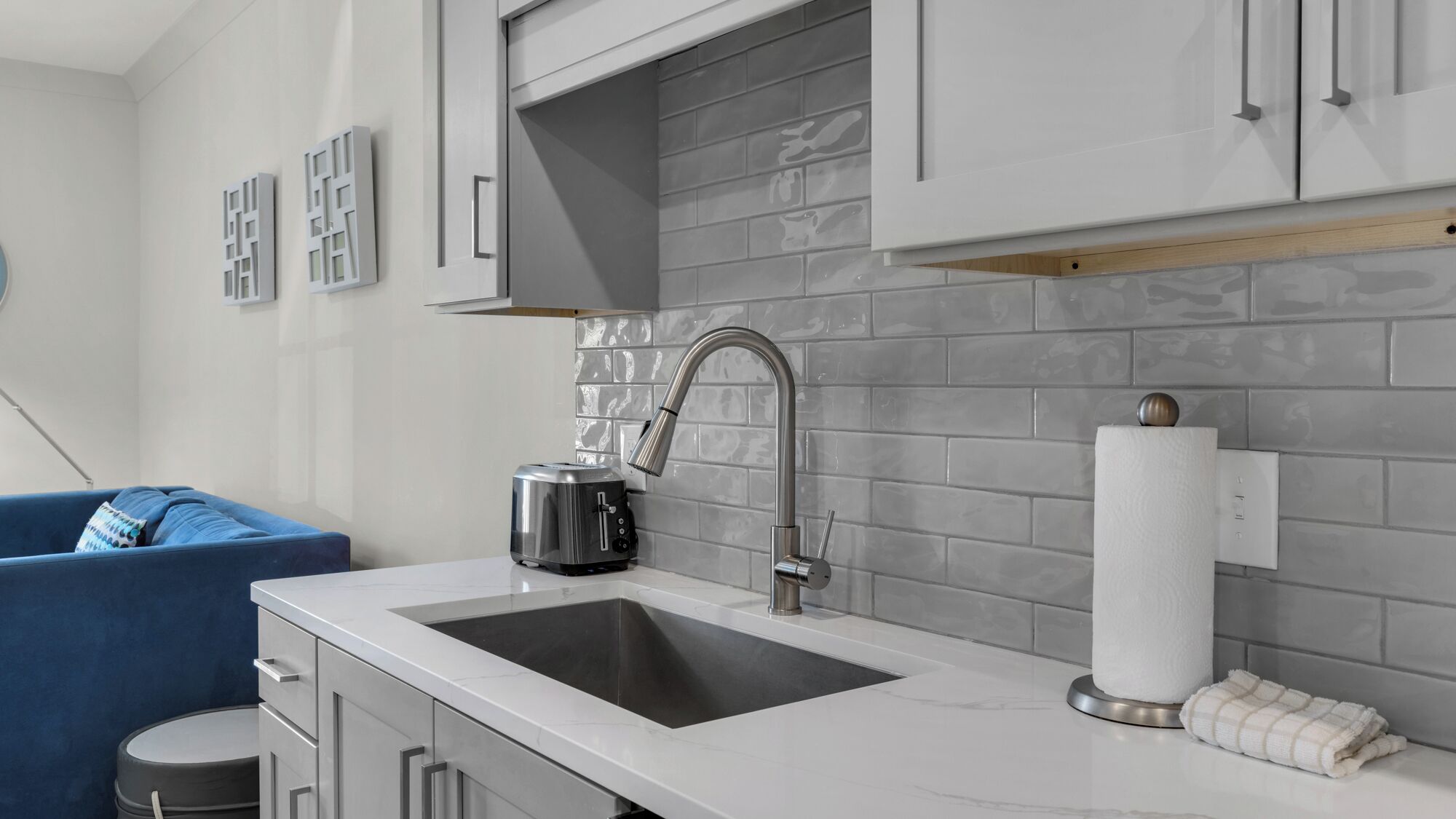 Una cocina moderna con un lavamanos de acero inoxidable, un tostador y un dispensador de toallas.
